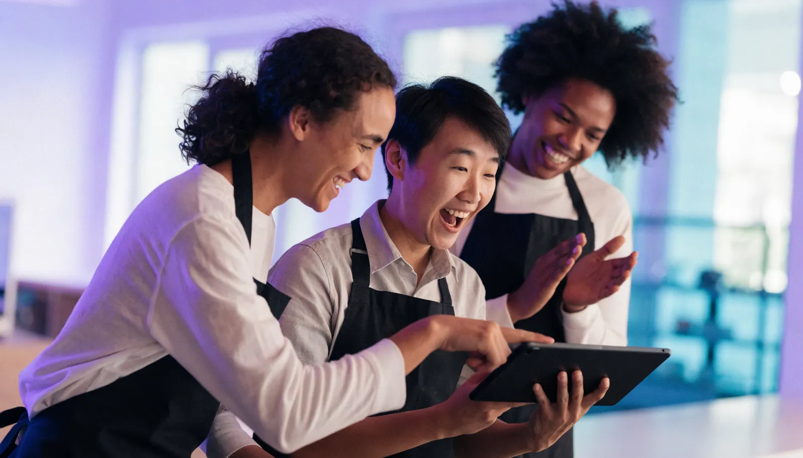 A team gathered around a tablet, reacting to their live review leaderboard
