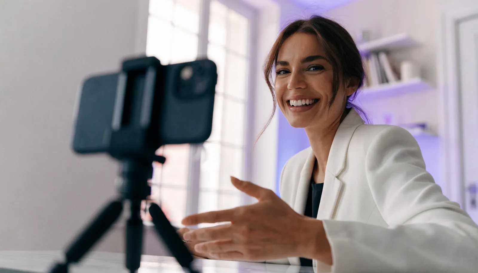A customer recording a video testimonial on a phone propped up at their desk